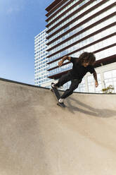 Young sportsman skateboarding on ramp at skateboard park - PNAF00401