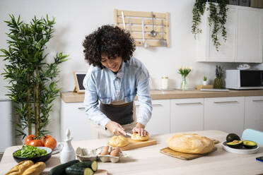 Young woman preparing vegan sandwiches in kitchen - GIOF10334