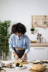 Young woman preparing vegan sandwiches in kitchen - GIOF10335