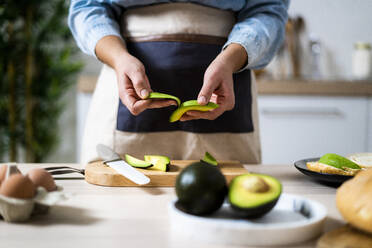 Mid section of woman peeling avocados - GIOF10339