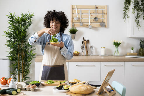Porträt einer jungen Frau, die in der Küche vegane Sandwiches zubereitet - GIOF10341