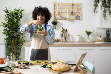Porträt einer jungen Frau, die in der Küche vegane Sandwiches zubereitet - GIOF10342