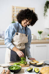 Portrait of young woman preparing vegan sandwiches in kitchen - GIOF10351