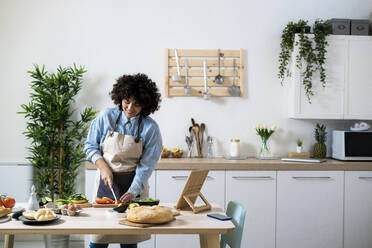 Young woman preparing vegan sandwiches in kitchen - GIOF10359