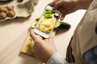 Hände einer jungen Frau, die mit ihrem Smartphone ein Foto von einem veganen Sandwich macht - GIOF10360