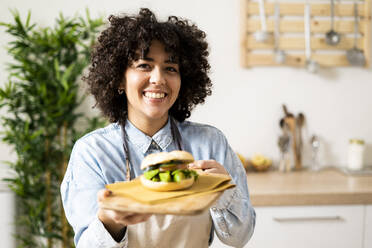 Portrait of young woman holding freshly made vegan sandwich - GIOF10362