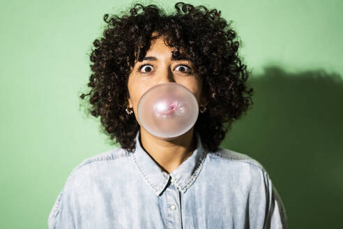 Porträt einer jungen Frau beim Blasen von Kaugummiblasen - GIOF10369
