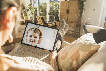 Little girl smiling on laptop screen during video call - UUF22303