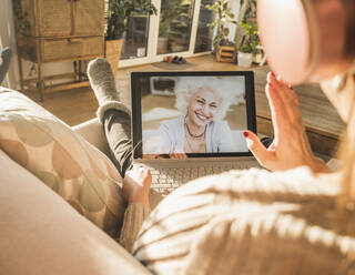 Senior woman smiling on laptop screen during video call - UUF22307