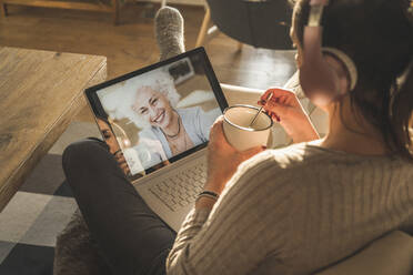 Senior woman smiling on laptop screen during video call - UUF22308