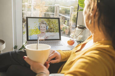 Two women talking during video call on laptop - UUF22313