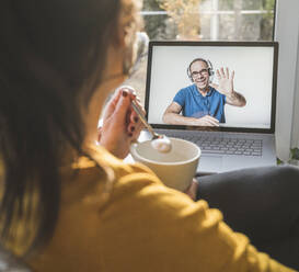 Man waving on screen during video call on laptop - UUF22315