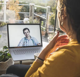 Lächelnde Ärztin auf dem Laptop-Bildschirm während eines Videoanrufs - UUF22318