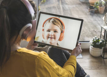 Kleines Mädchen, das während eines Videoanrufs auf dem Bildschirm eines digitalen Tablets lächelt - UUF22325