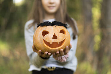 Mädchen hält Halloween-Kürbis, während sie im Park steht - XCF00307