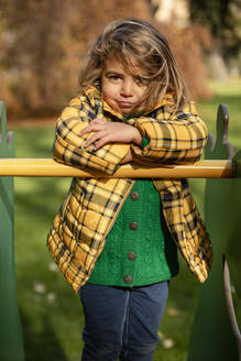 Girl standing with arms crossed on play equipment at park - MCVF00684