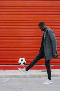 Mann schlägt Fußball beim Spielen gegen eine rote Wand - EGAF01327