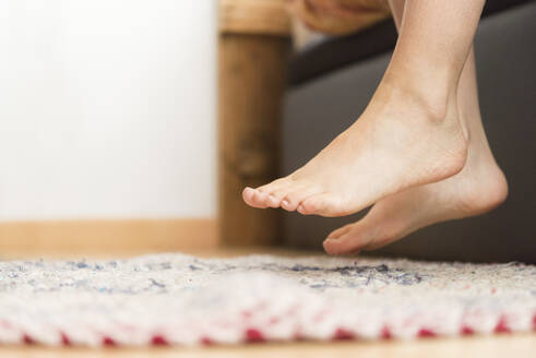 Frau stellt ihre nackten Füße auf einen handgefertigten Teppich zu Hause - SKCF00713