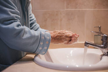 Ältere Frau beim Händewaschen am Waschbecken zu Hause - LJF02016