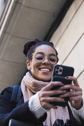 Lächelnde schöne junge Frau mit Smartphone - PNAF00441