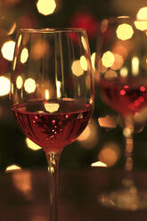 Rose wine in shiny wineglass in front of Christmas tree - JTF01755