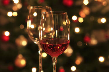Rosenwein in glänzenden Weingläsern vor dem Weihnachtsbaum - JTF01757