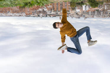 Auf den Kopf gestelltes Bild eines jungen Mannes, der einen Handstand gegen die Stadt macht - GGGF00571