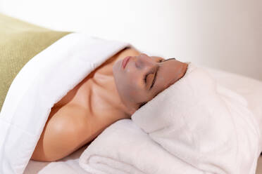 Young female customer lying on massage table at health spa - OCMF01906