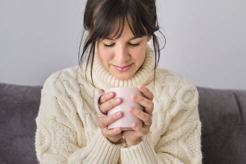 Frau trinkt im Winter zu Hause Kaffee in einem Becher - AODF00093