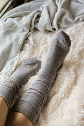 Frau in Socken, die sich zu Hause auf einem Fell entspannt - AODF00118