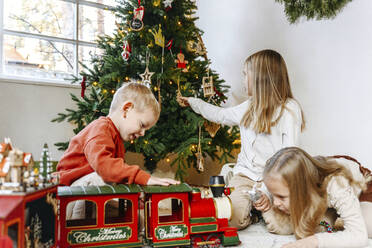 Geschwister spielen mit Spielzeug zu Hause während der Weihnachtszeit - EYAF01444