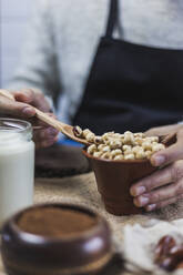 Hands of man picking hazelnuts with wooden spoon - MGRF00109