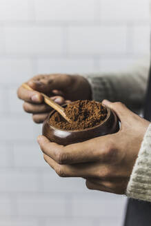 Hands of man holding bowl of cocoa powder - MGRF00112