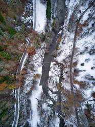 Luftaufnahme einer Landstraße, die sich durch eine schneebedeckte Landschaft zieht - KNTF06044