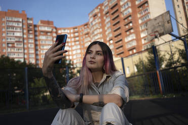 Young woman talking selfie through mobile phone in sports court - VPIF03338