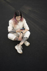 Modische junge Frau mit Tätowierung, die ihr Smartphone in Spots benutzt Gericht - VPIF03339