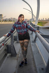 Junge Frau mit Tattoo auf einer Brücke am Straßenrand stehend - VPIF03379