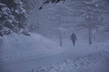 Ältere Frau geht in den Ferien auf einer verschneiten Straße spazieren - MRF02413