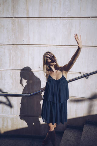 Young woman stretching hand while standing on steps stock photo