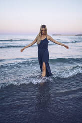 Young woman standing with arms outstretched while playing at Platja de Llevant beach - RSGF00466