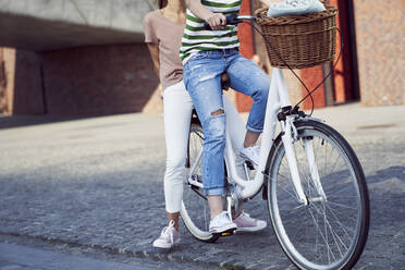 Female friends traveling on bicycle in city during weekend - ABIF01284