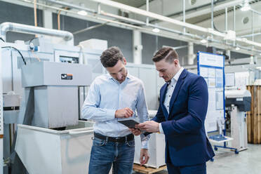 Business people discussing over digital table while standing in industry - DIGF13534