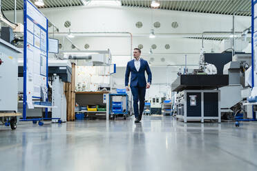 Businessman looking around while walking in factory - DIGF13537