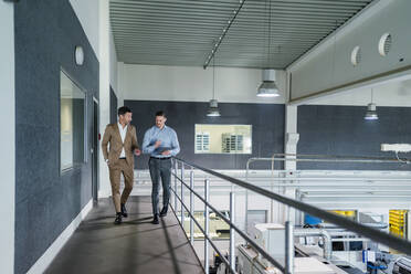 Businessman with male coworker in walkway at industry - DIGF13608