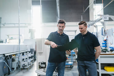 Male engineer with coworker reading file document in industry - DIGF13626