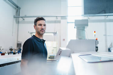 Male engineer looking away while standing in industry - DIGF13633