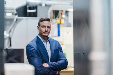 Confident businessman with arms crossed in industry - DIGF13652