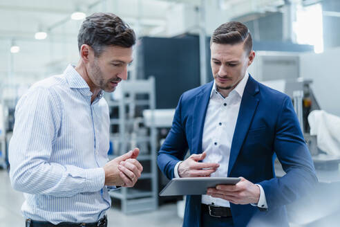 Geschäftsleute arbeiten gemeinsam an einem digitalen Tablet in der Industrie - DIGF13670