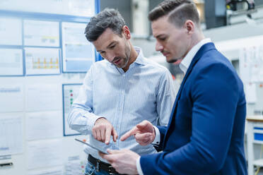 Male coworkers discussing business strategy over digital tablet in factory - DIGF13671