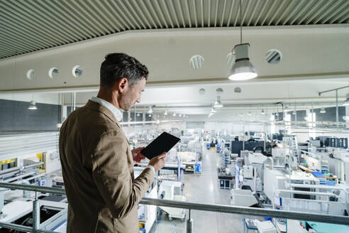 Männlicher Fachmann im Anzug mit digitalem Tablet in einer Fabrik - DIGF13696